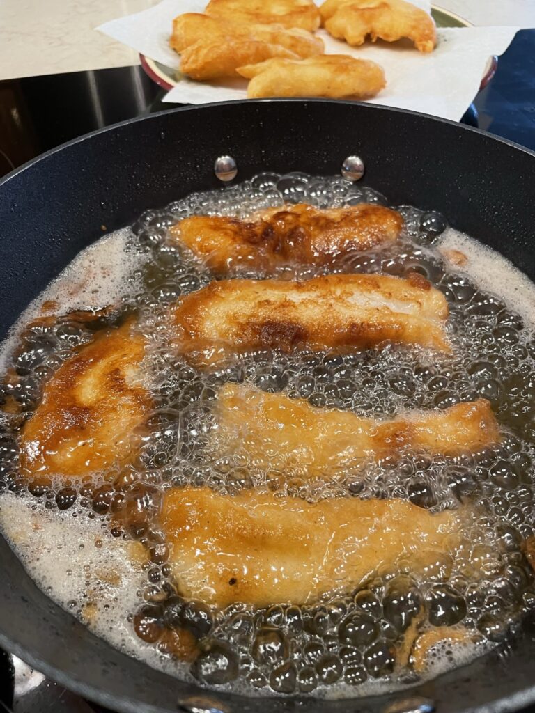 Pan frying beer battered fish.