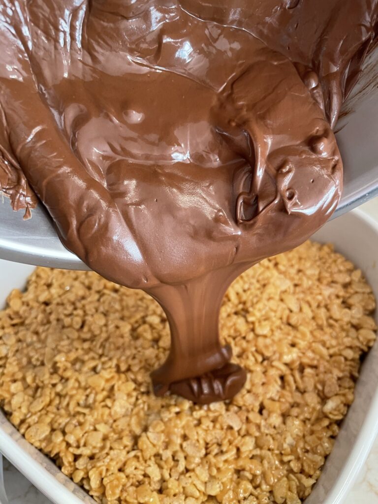 Pouring chocolate over no-bake scotcheroos.