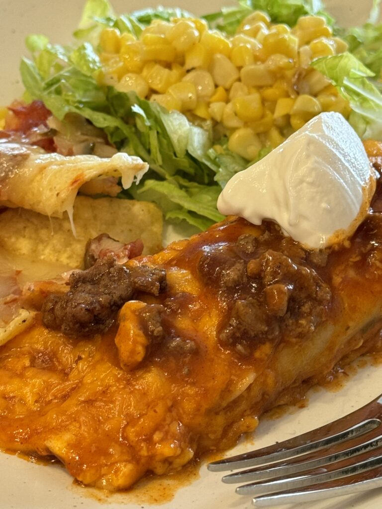 Beef Enchiladas with shredded lettuce and corn.